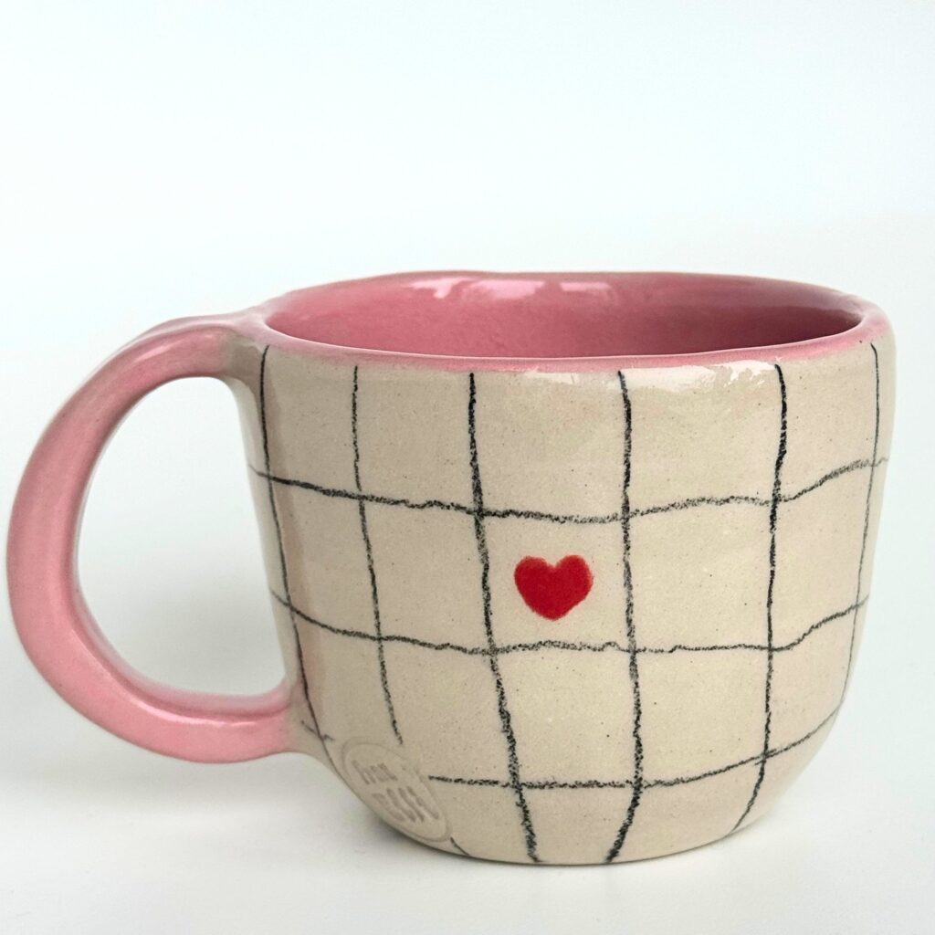 andgemachte Keramik Tasse mit rosa Glasur innen, feinem Karomuster und kleinem roten herz